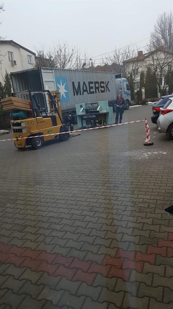 A guillotine being moved by forklift next to a Maersk container truck