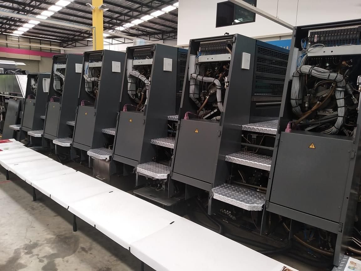 Row of sheetfed offset printing units with their side panels open for inspection