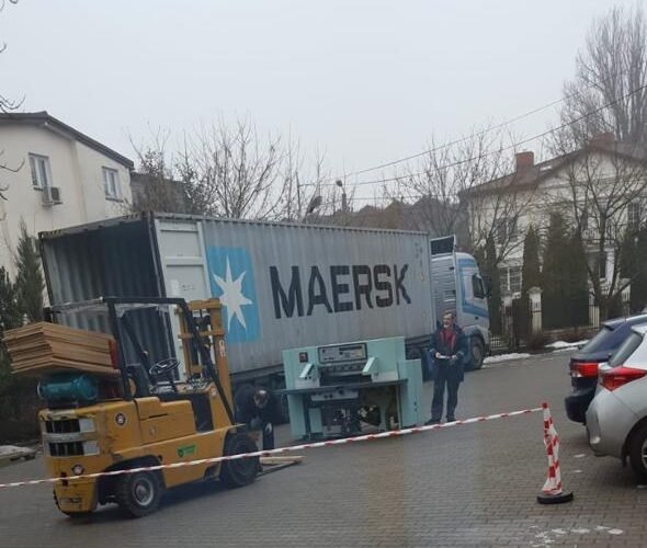 Teal POLAR guillotine being unloaded from a Maersk shipping container with a forklift